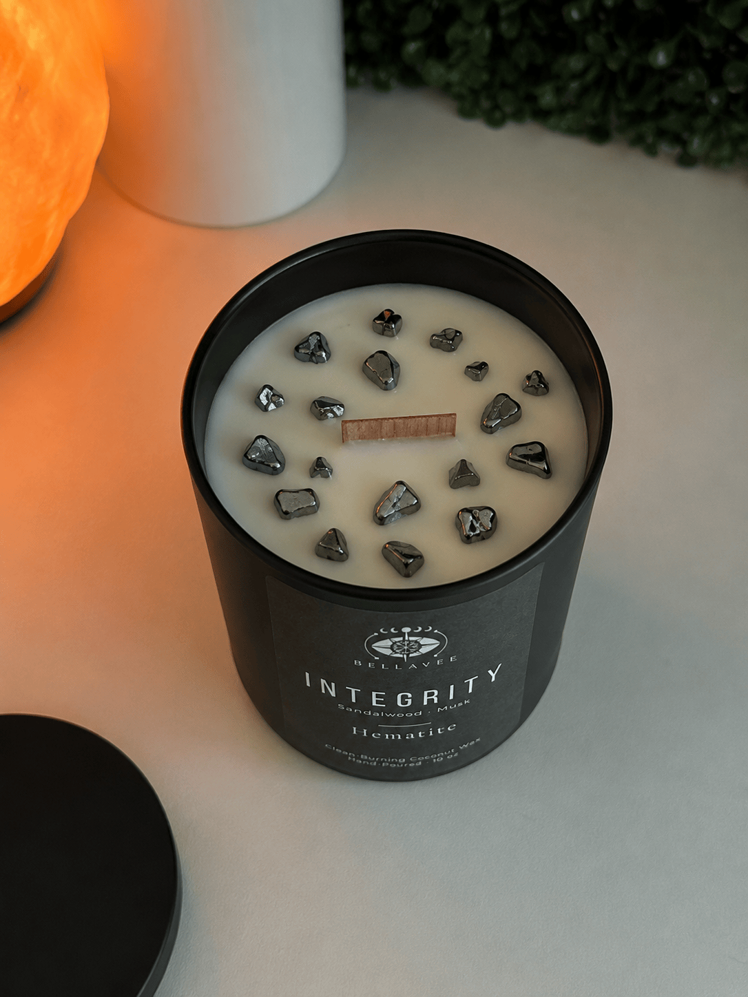 Candle with decorative stones in a black container labeled &
