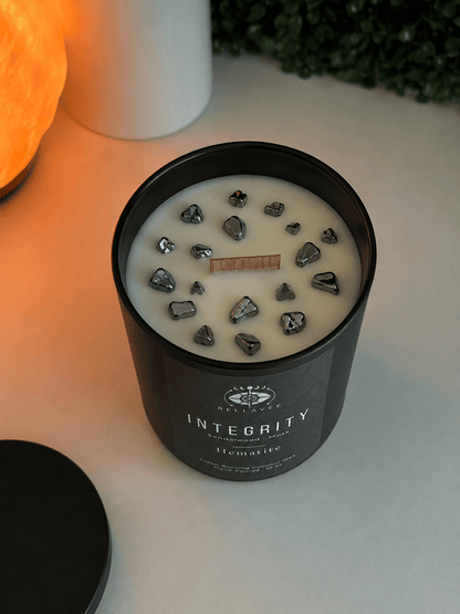Candle with decorative stones in a black container labeled &