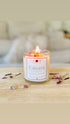 Lit elevate amethyst crystal candle with dried botanicals and crystals surrounding it