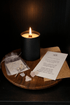 Candle burning on a wooden surface with ritualistic items and a piece of paper.