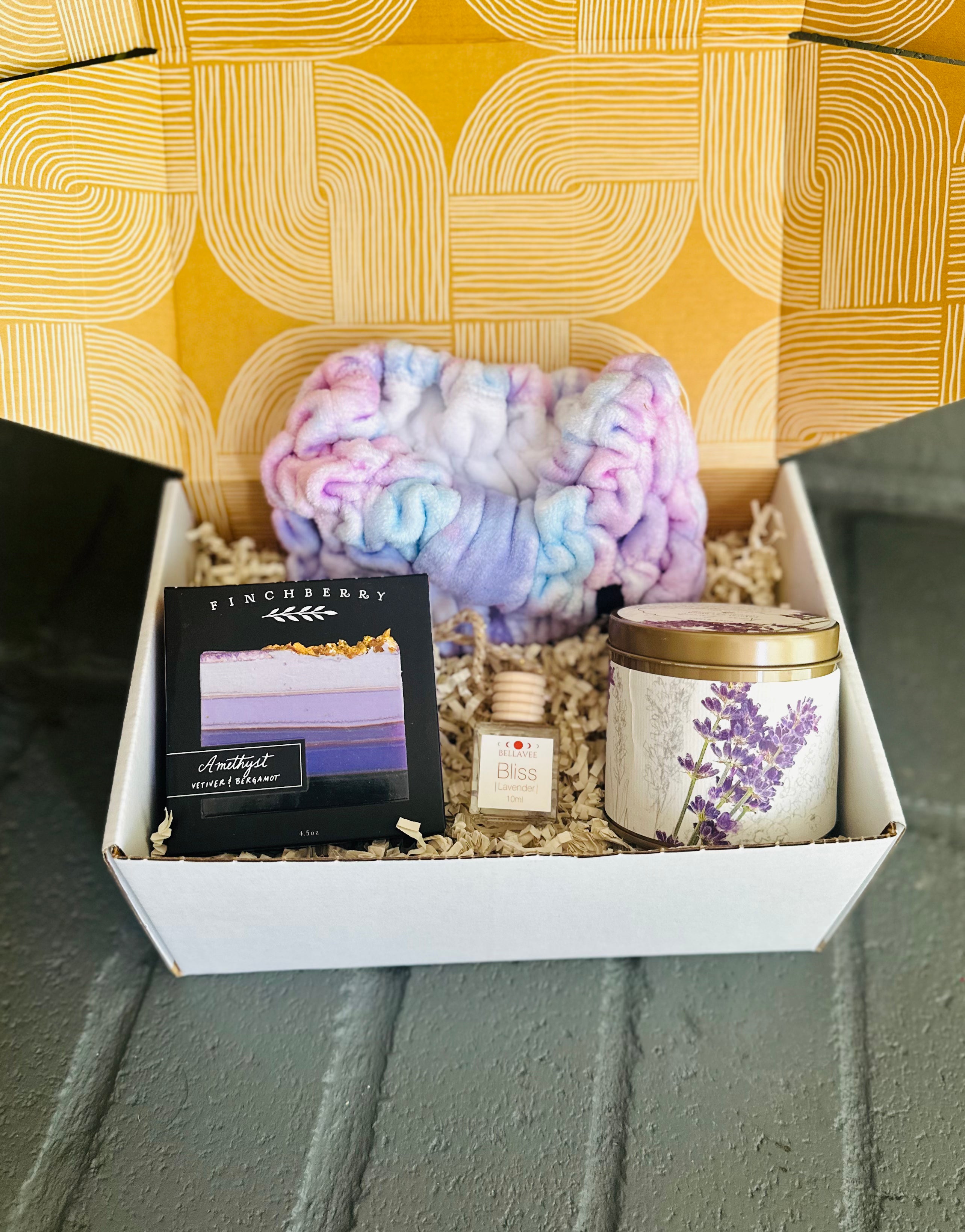 Lavender Bliss Gift Box with Amethyst soap, lavender-scented car diffuser, Roman Lavender candle, and a purple tie-dye spa headband