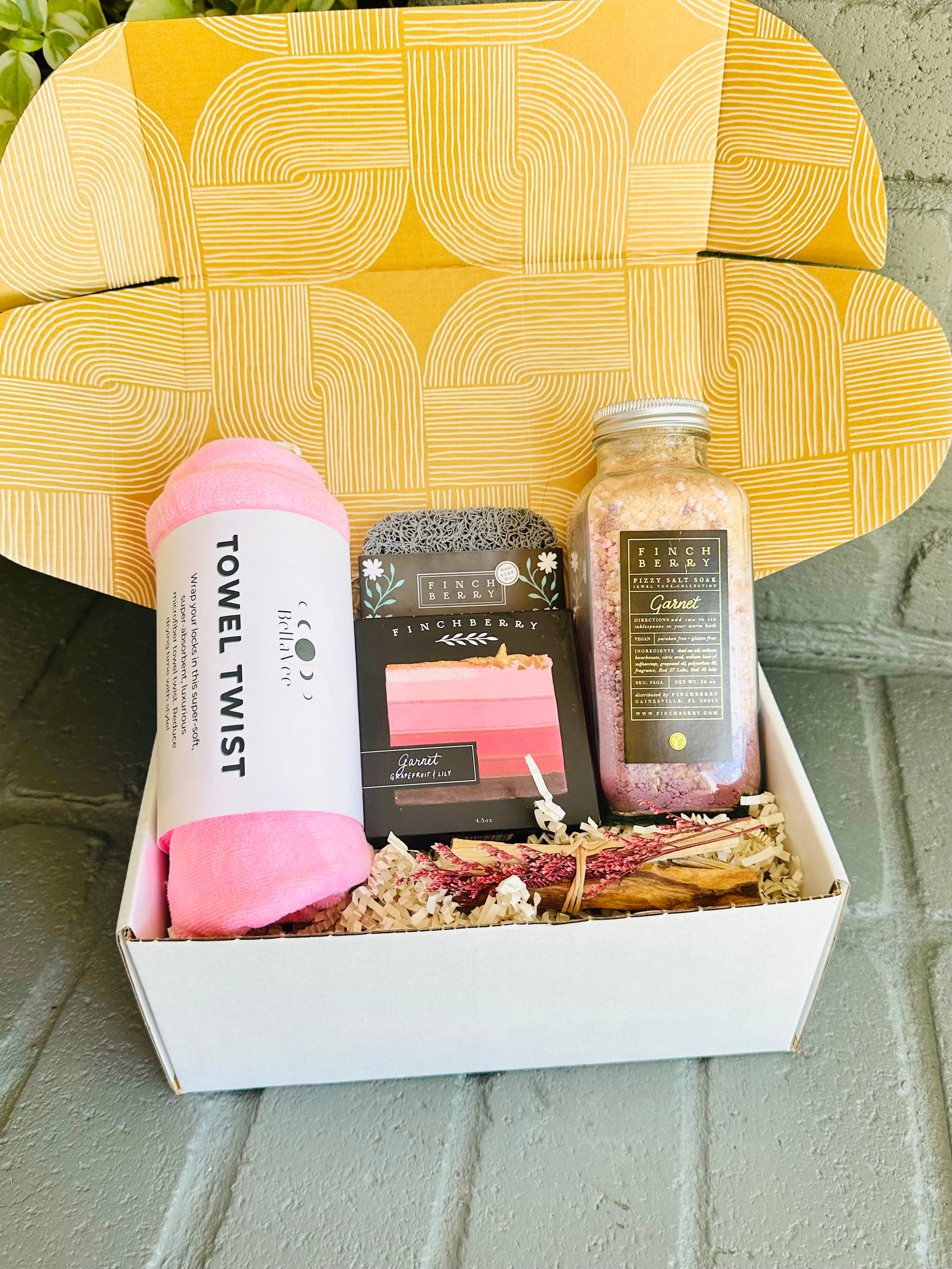 garnet glow gift box with pink towel twist, garnet bath fizzies, luxury body soap, soap saver, and palo santo for a soothing self-care routine