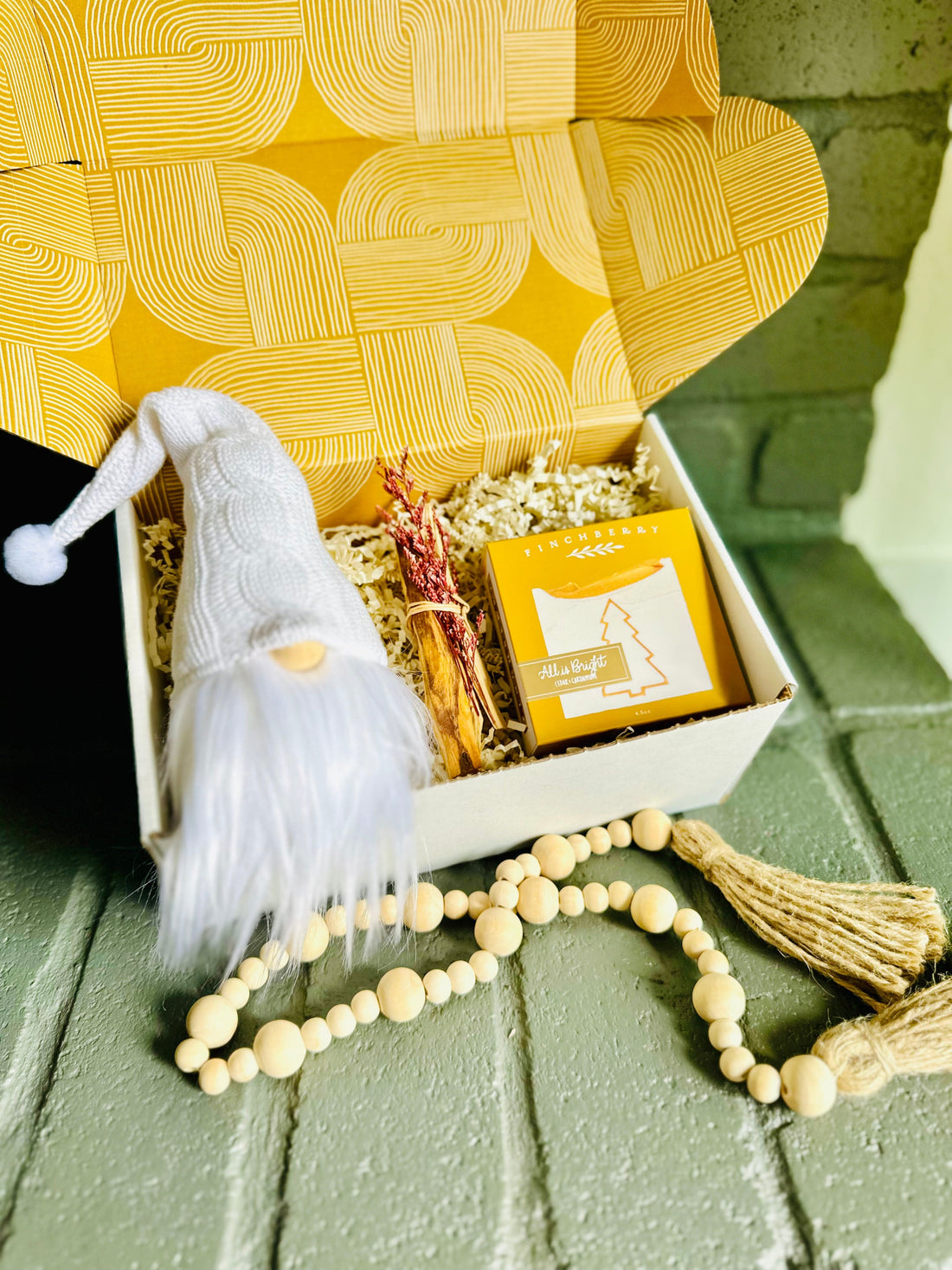 Bring holiday cheer with the Winter White Gift Box featuring a cute gnome, luxurious soap, Palo Santo, and wooden bead strand