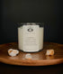 Unwind Prehnite crystal ritual candle in a clear glass jar styled on a wooden surface.