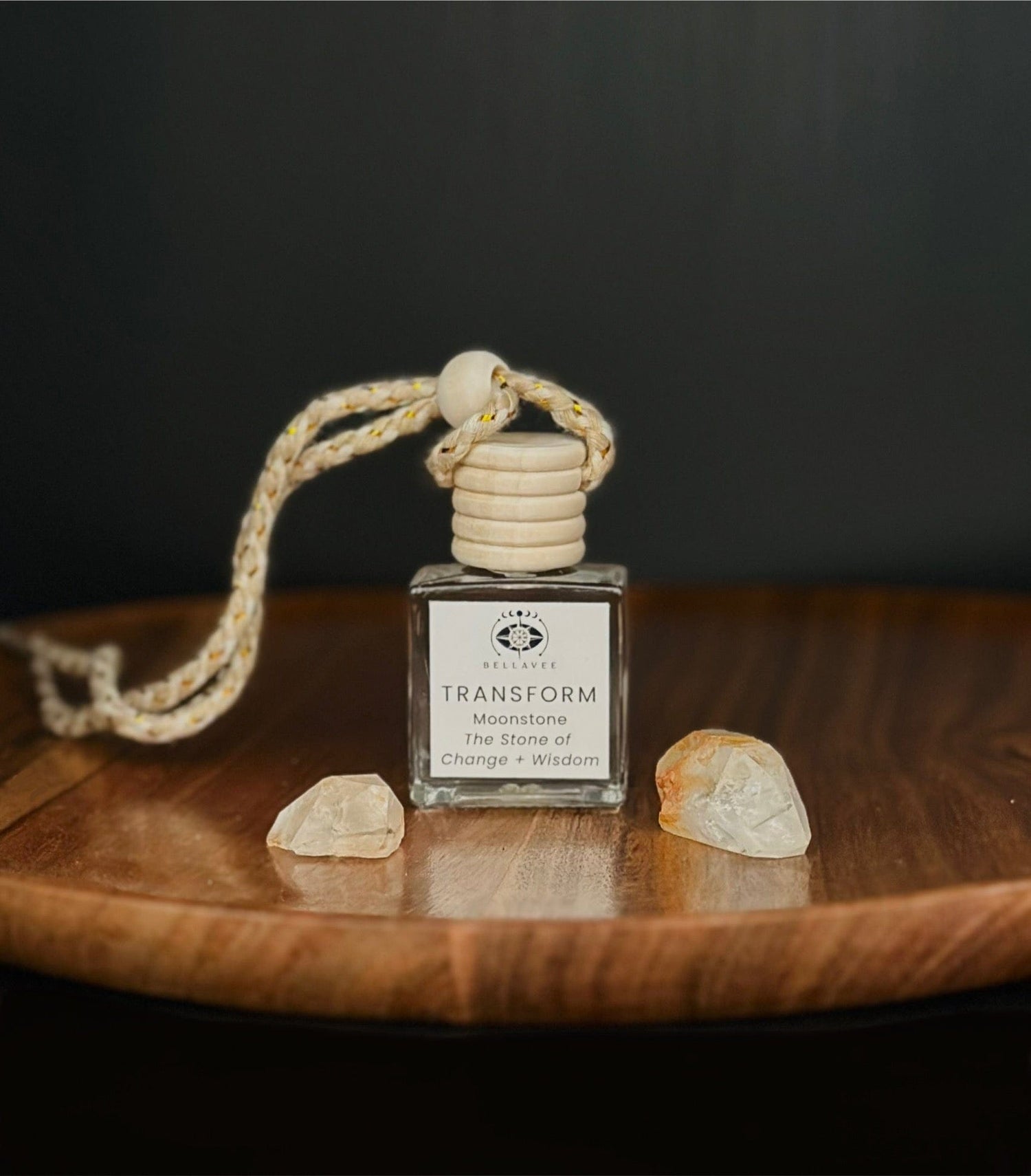 Crystal-infused diffuser labeled “Transform” with Moonstone stones on a wooden surface.