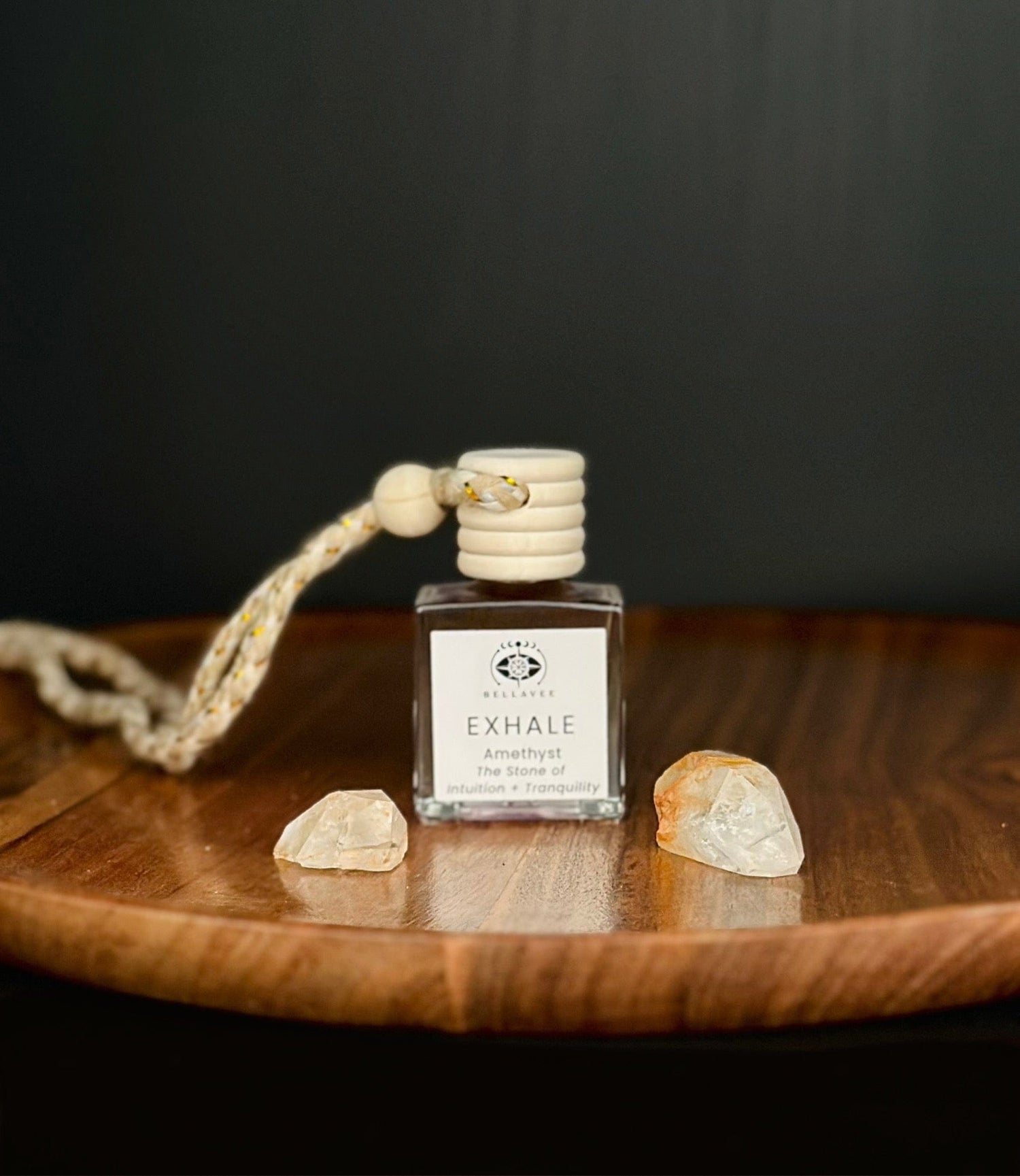 Crystal-infused diffuser labeled “Exhale” with Amethyst stones on a wooden surface.