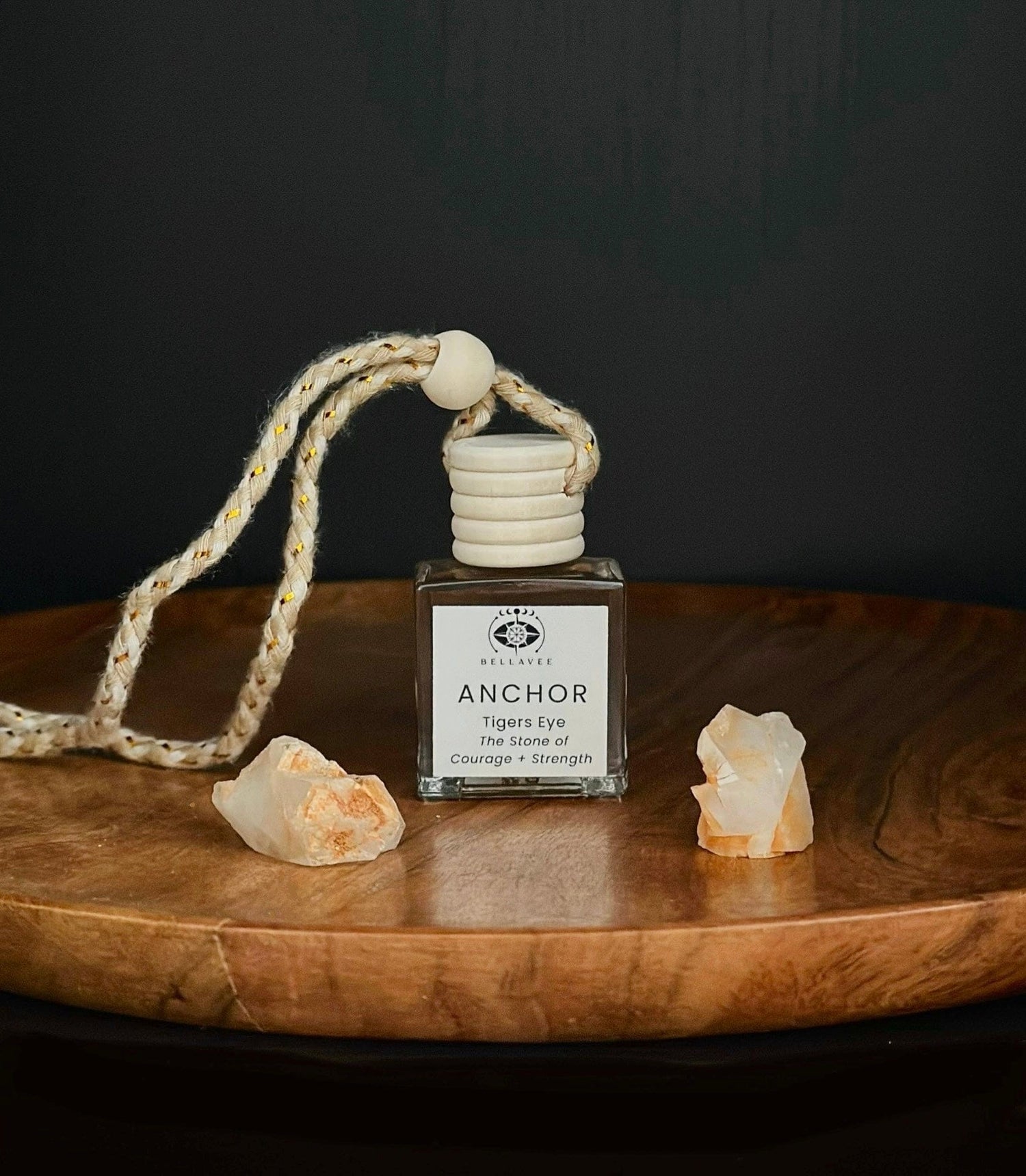 Crystal-infused diffuser labeled “Anchor” with Tiger’s Eye stones on a wooden surface.