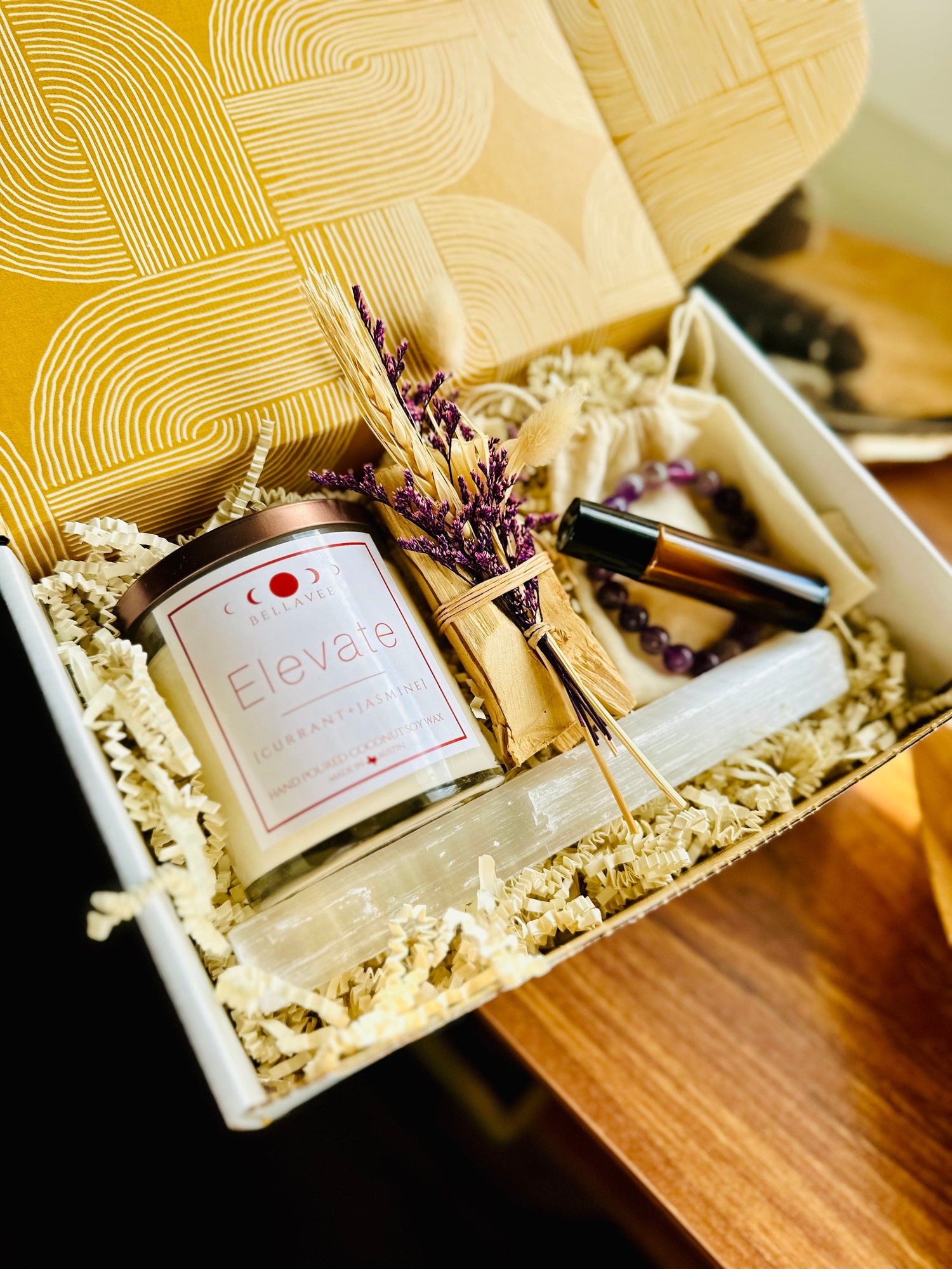 Elevate Amethyst topped crystal Candle wellness gift box with essential oil roll on and Palo Santo bundle with amethyst bracelet and selenite wand. Purple accents beautifully packaged.