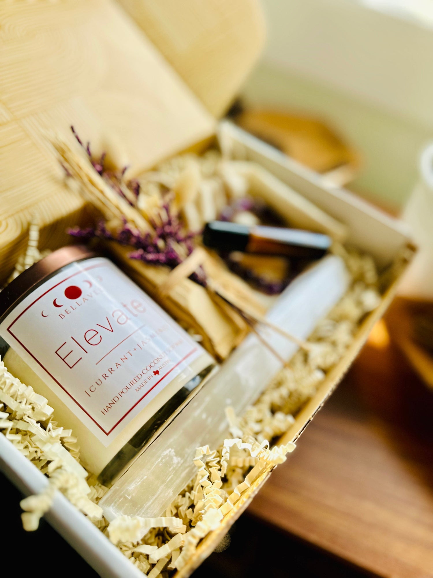 Elevate crystal Candle wellness gift box with essential oil roll on and Palo Santo bundle with amethyst bracelet and selenite wand. Purple accents beautifully packaged.