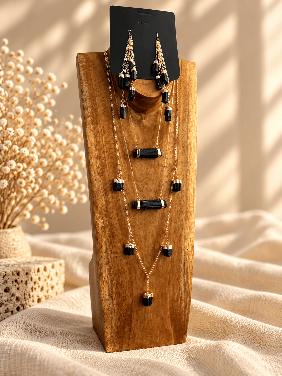 Five-stone crystal drop earrings styled with layered gold crystal necklaces on wooden jewelry display