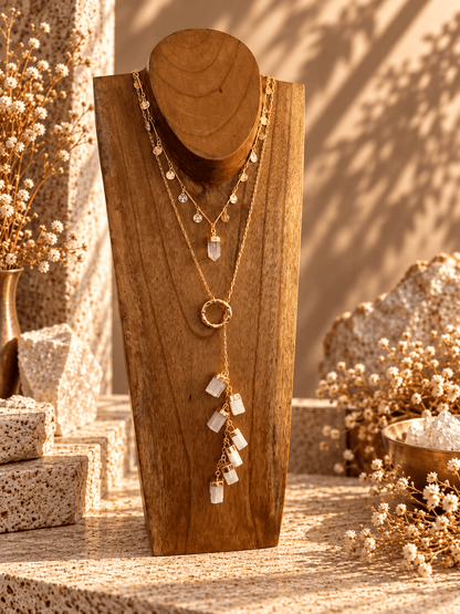 Seven-stone Selenite drop necklace layered with crystal necklaces on wooden jewelry display