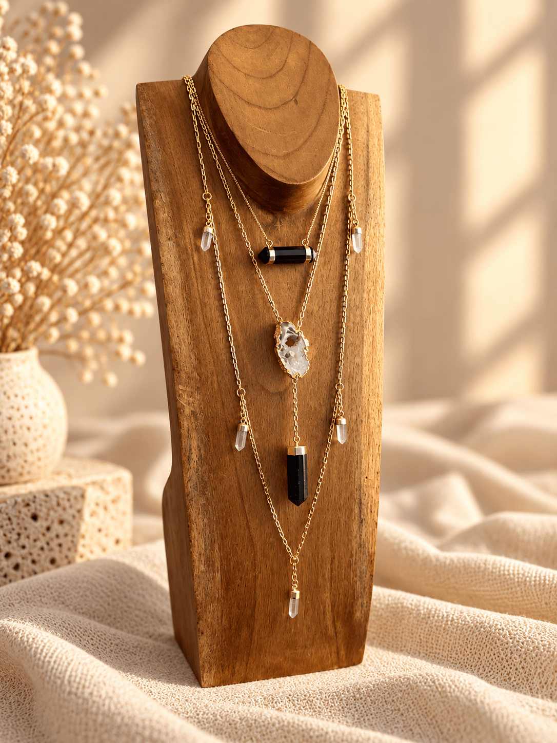 Agate slice crystal drop necklace layered with gold crystal necklaces on wooden jewelry display