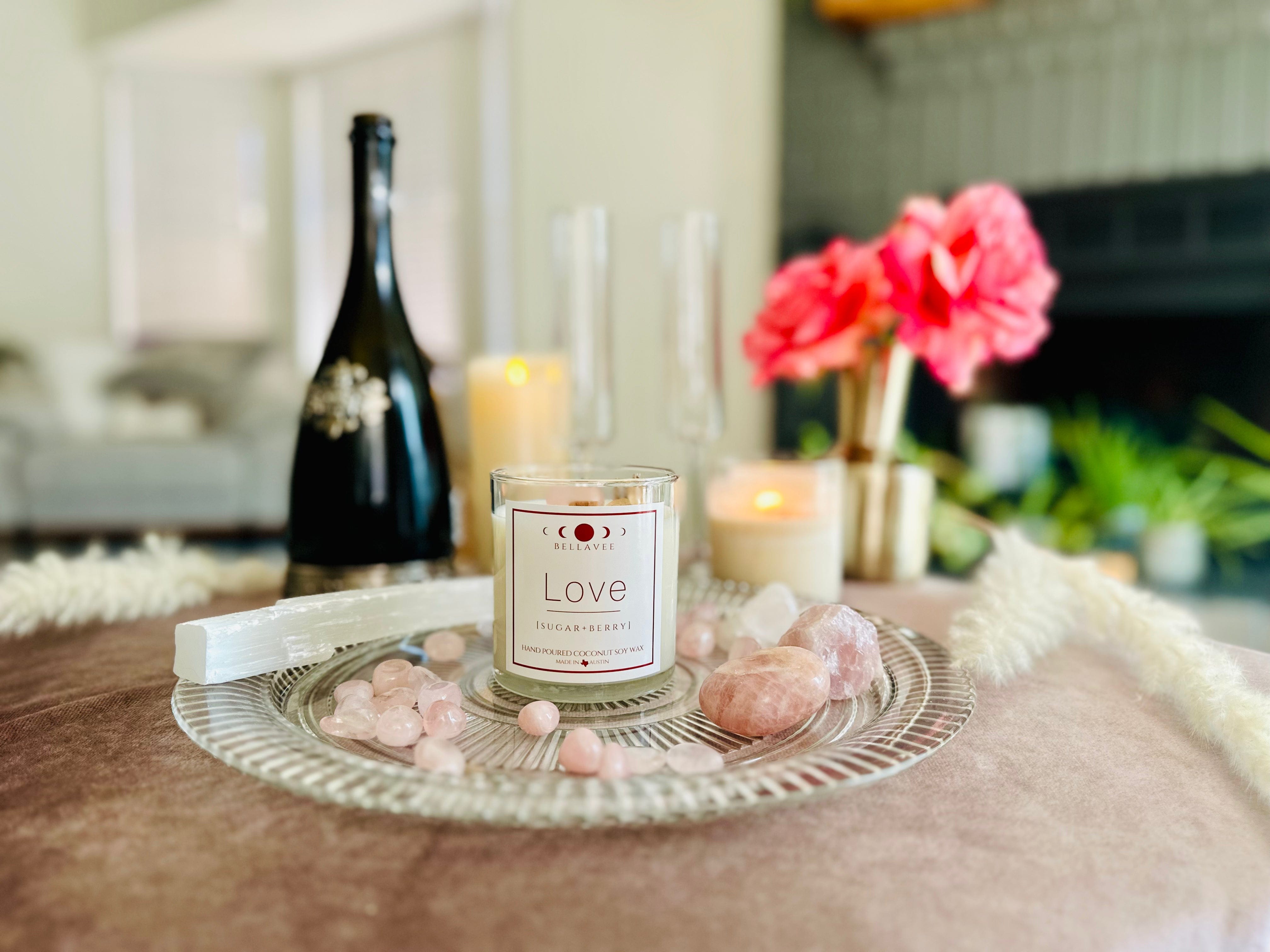 Love rose quartz crystal candle with champagne and champagne flutes and rose quartz and selenite laid out in romantic setting