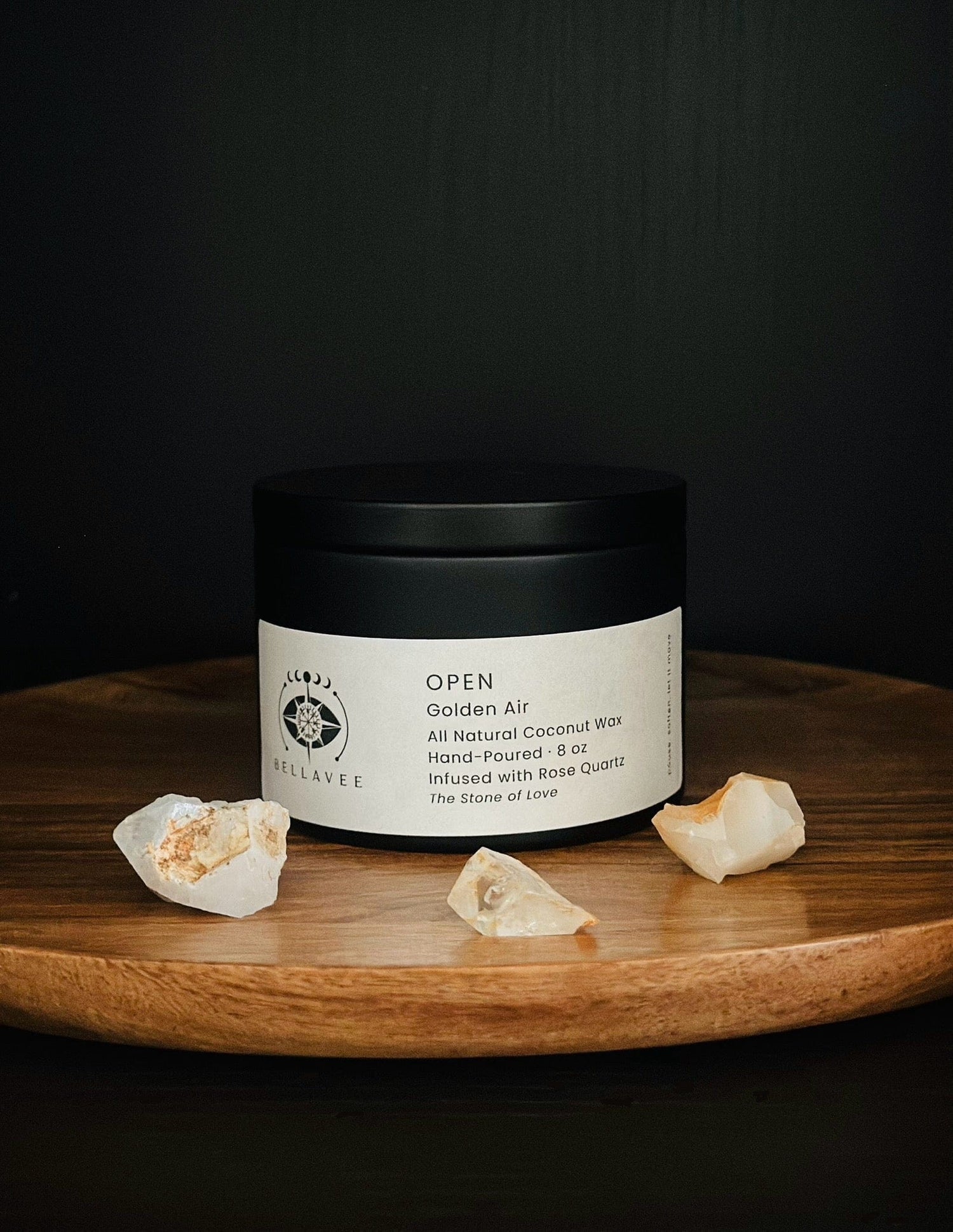 Open Rose Quartz crystal candle tin representing love and heart energy on wooden tray with crystals and dark background.