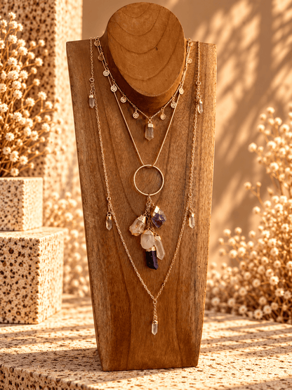 Power of Five crystal drop necklace layered with gold crystal necklaces on wooden jewelry display