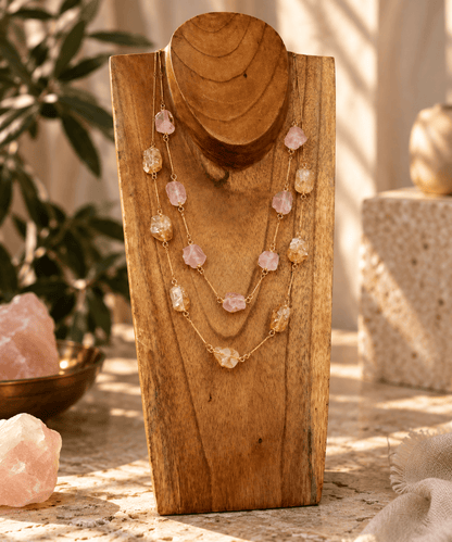 Rose Quartz and Citrine seven stone crystal necklaces on gold chains displayed on a wooden jewelry stand