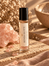 BellaVee SENSUALITY Ritual Oil roll-on with rose quartz chips, displayed upright on natural stone with warm golden lighting and soft botanical accents.