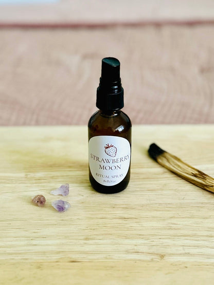 Close-up of BellaVee ritual spray bottle with crystals and Palo Santo nearby.