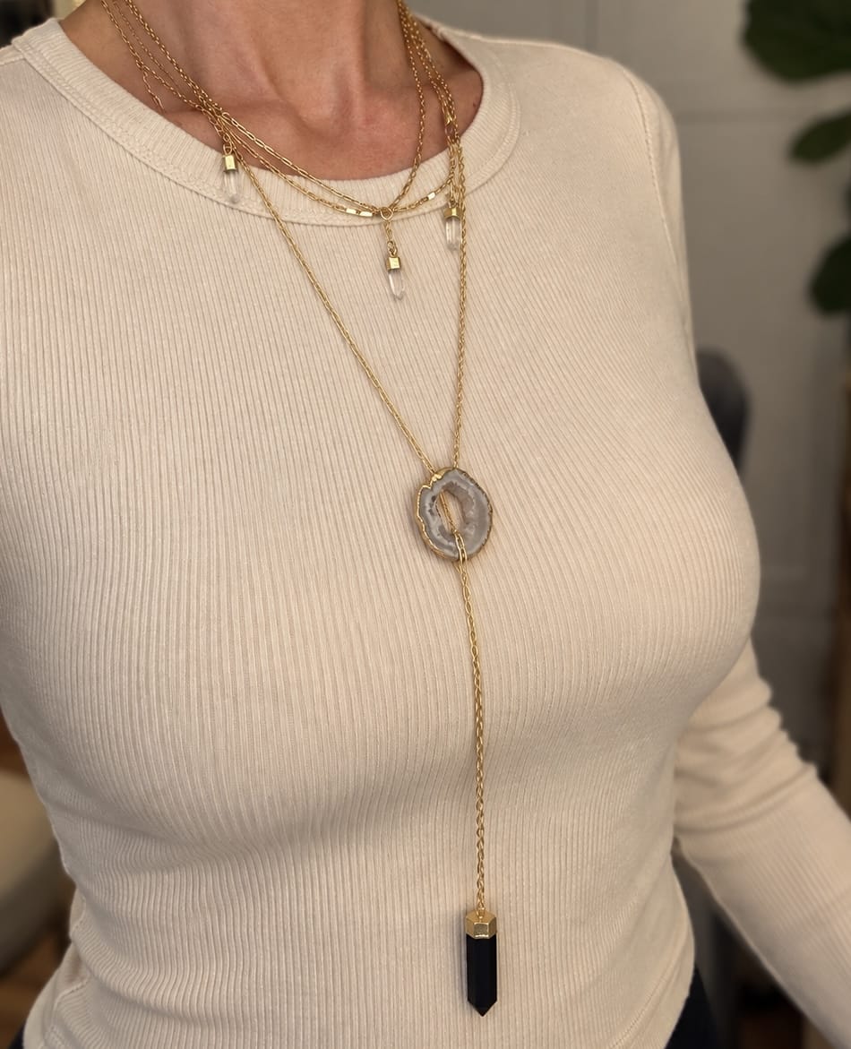 Long Agate slice crystal necklace worn in a layered gold jewelry stack