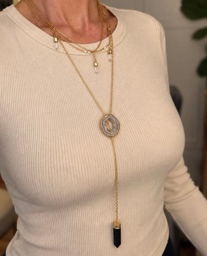 Long Agate slice crystal necklace worn in a layered gold jewelry stack