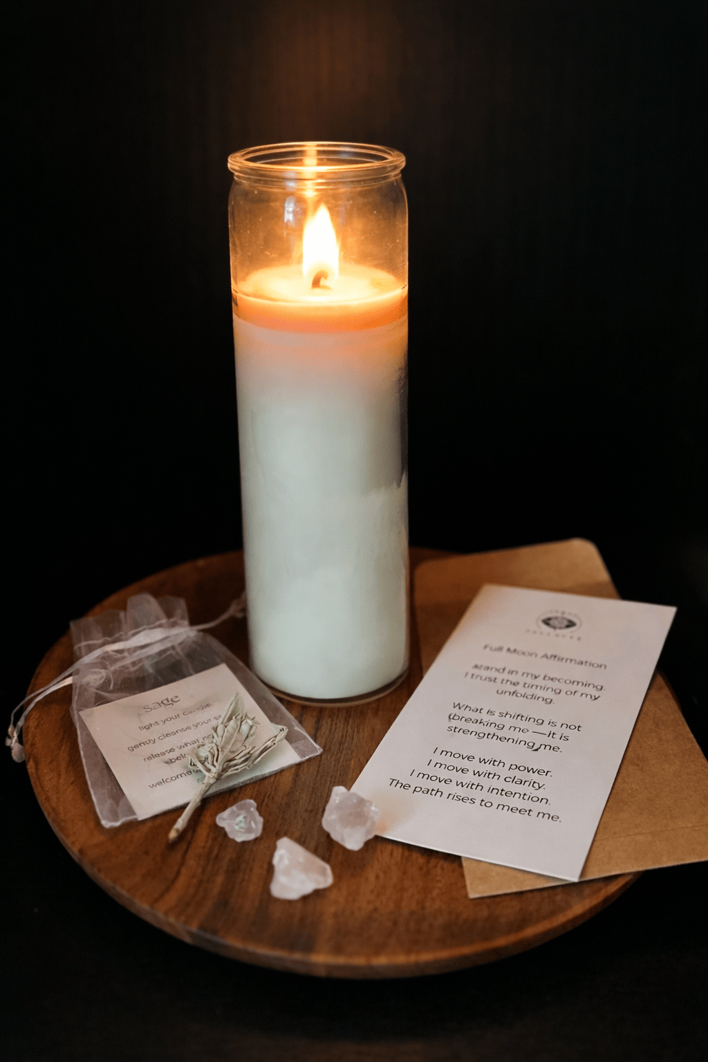 Candle on a wooden tray with cards and crystals against a dark background
