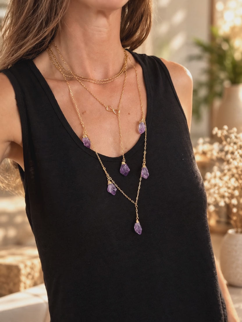 Amethyst Infinity Drop necklace worn and styled with layered gold crystal jewelry to show its adjustable length and drop