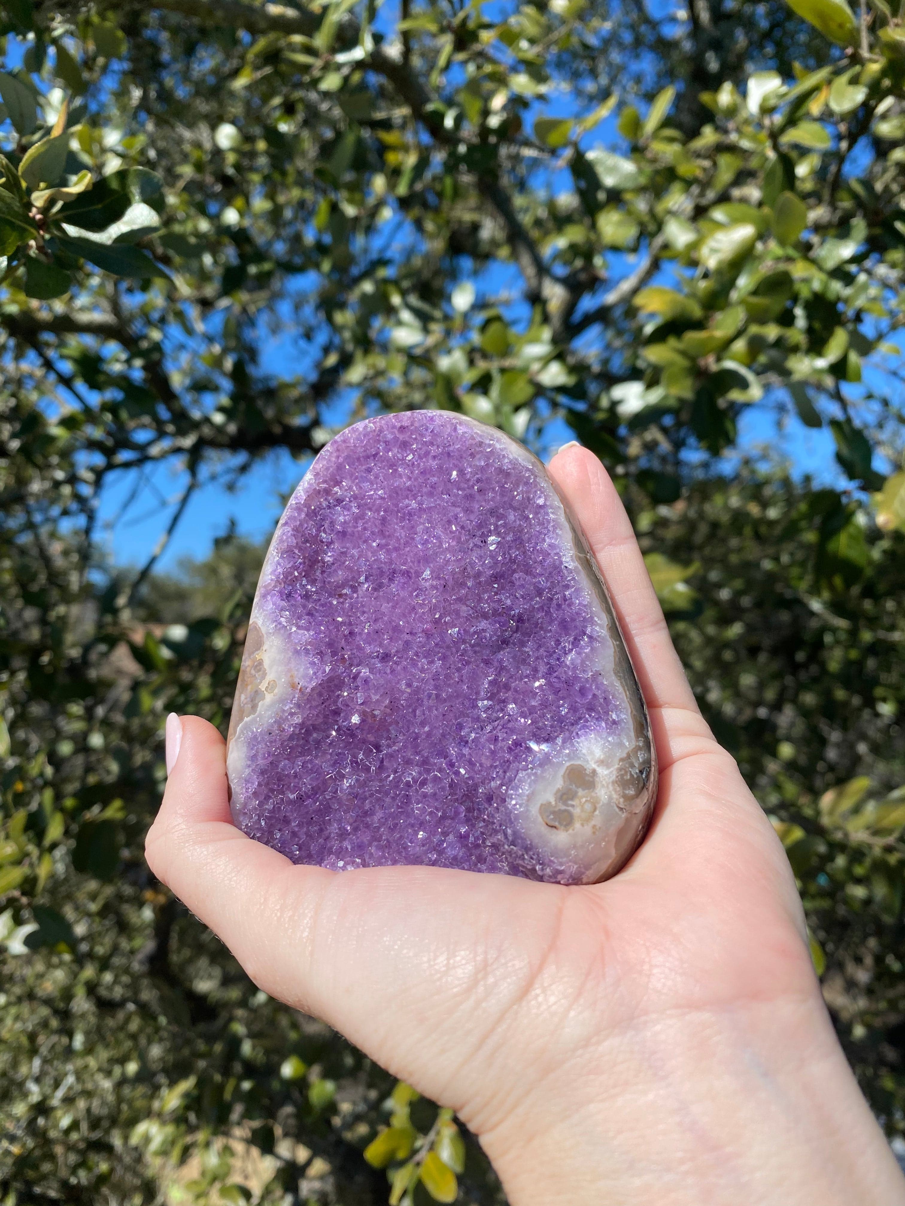 Uruguayan Amethyst geode with purple crystals and Agate edging, sparkling under the sun.