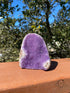 Uruguayan Amethyst geode with bright purple crystals and a banded Agate edge in neutral tones.