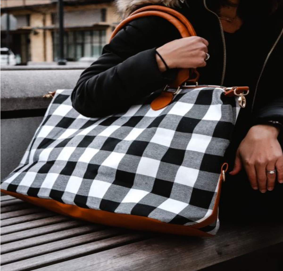 Person carrying Buffalo Plaid Weekender Bag with cognac straps, showcasing its spacious design and travel-ready features