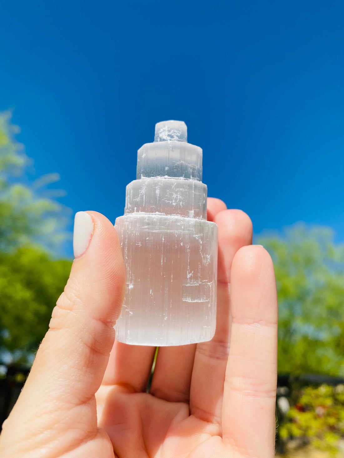 Held up close, the four-tier Selenite Tower reveals its smooth, detailed structure, promoting peace, clarity, and removing negative energy