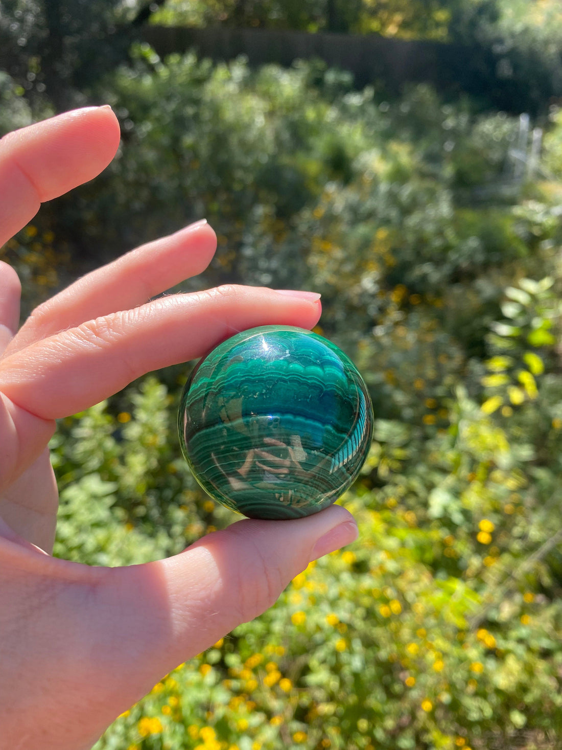 Malachite Sphere with varying green hues, a powerful protection stone that absorbs negative energies and pollutants from the body and atmosphere
