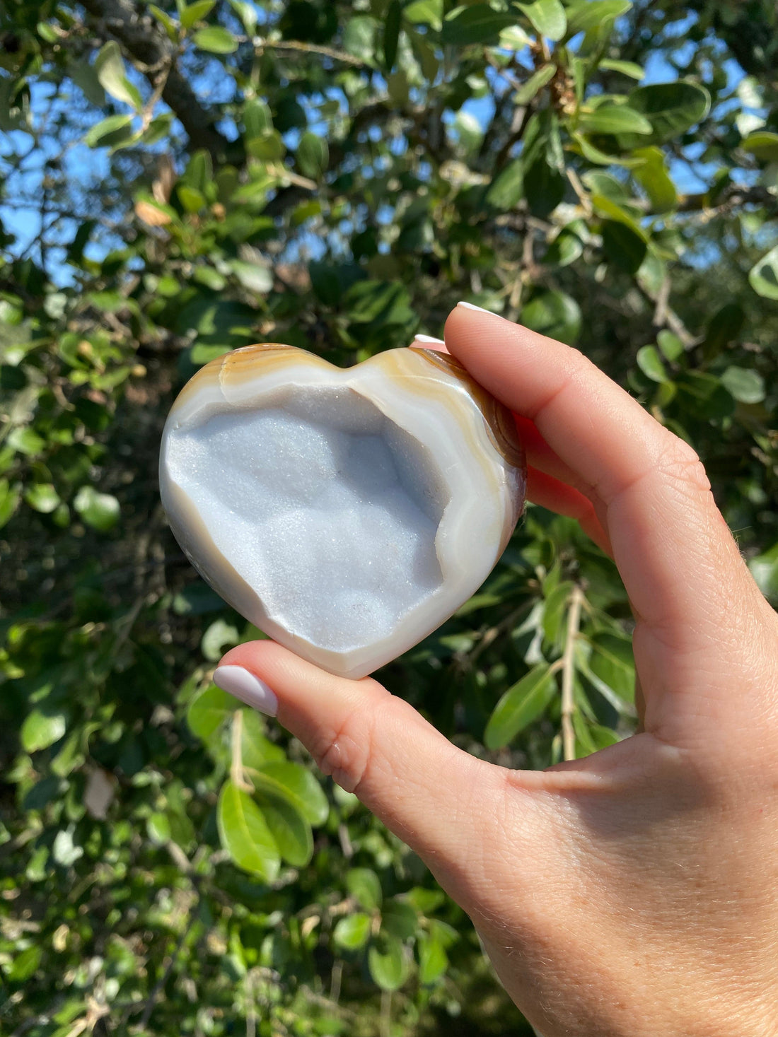 Held up close, the Snow White Agate Heart reveals stunning gold, tan, and cream bands, with shimmering gold glitter throughout its backing