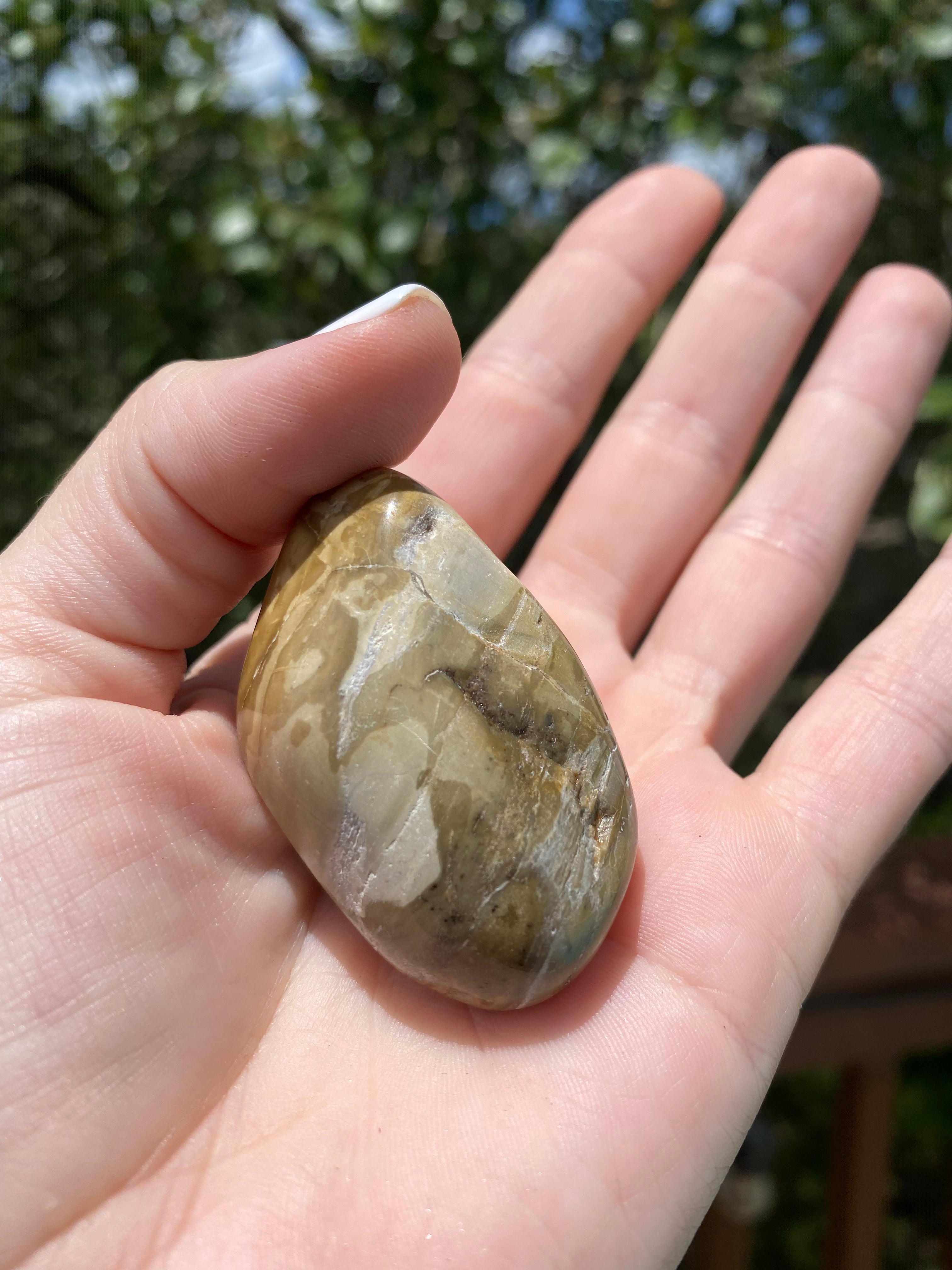 Brown Jasper tumble stone held in hand, offering grounding energy and a sense of balance and calm