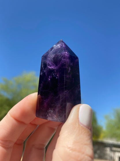 Under sunlight, the Purple Fluorite Mini Tower glows with vibrant shades of purple, highlighting its spiritual and protective energy