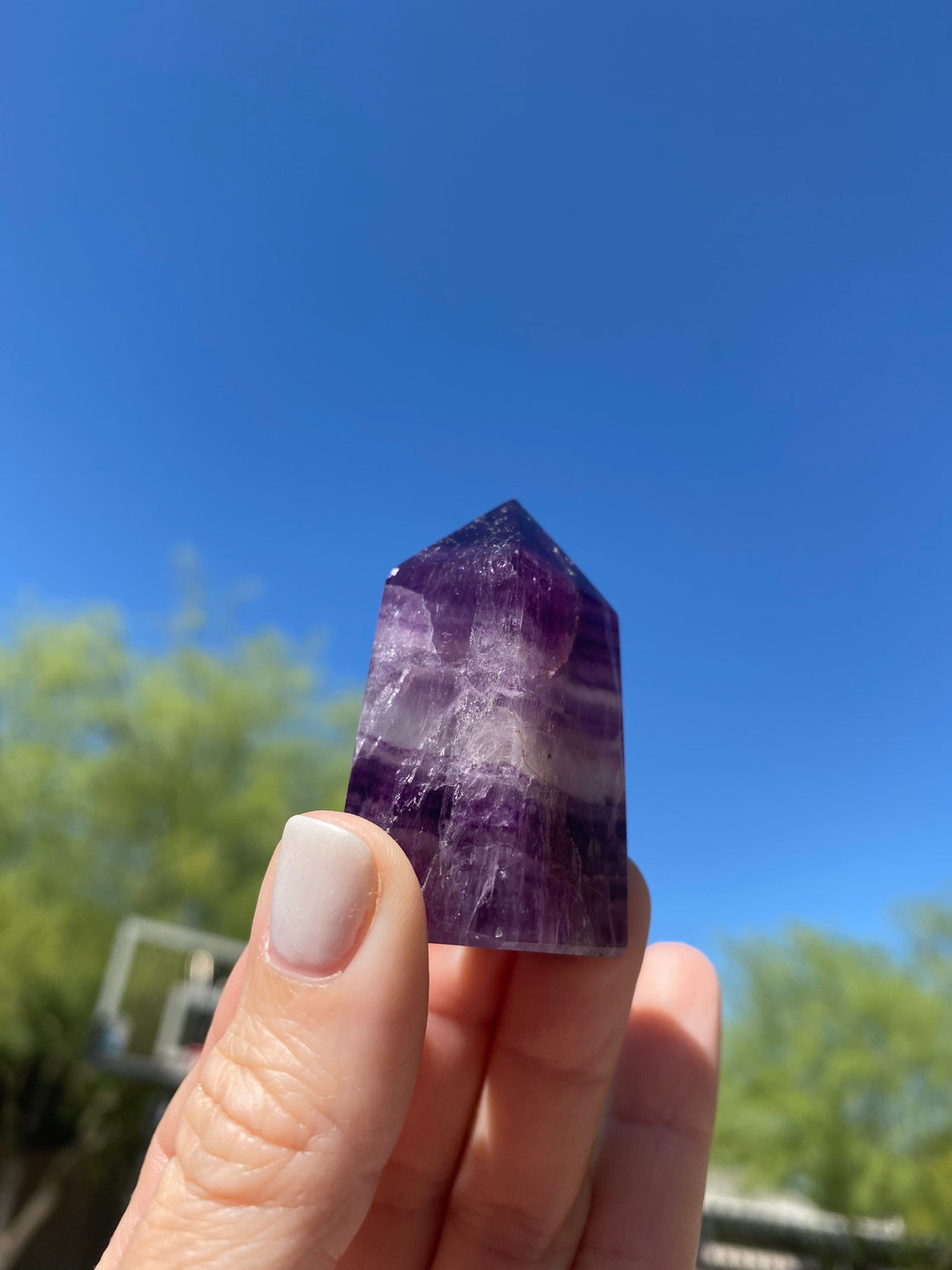 Purple Fluorite Mini Tower shines beautifully under the sun, enhancing its deep violet hues and natural crystal formations