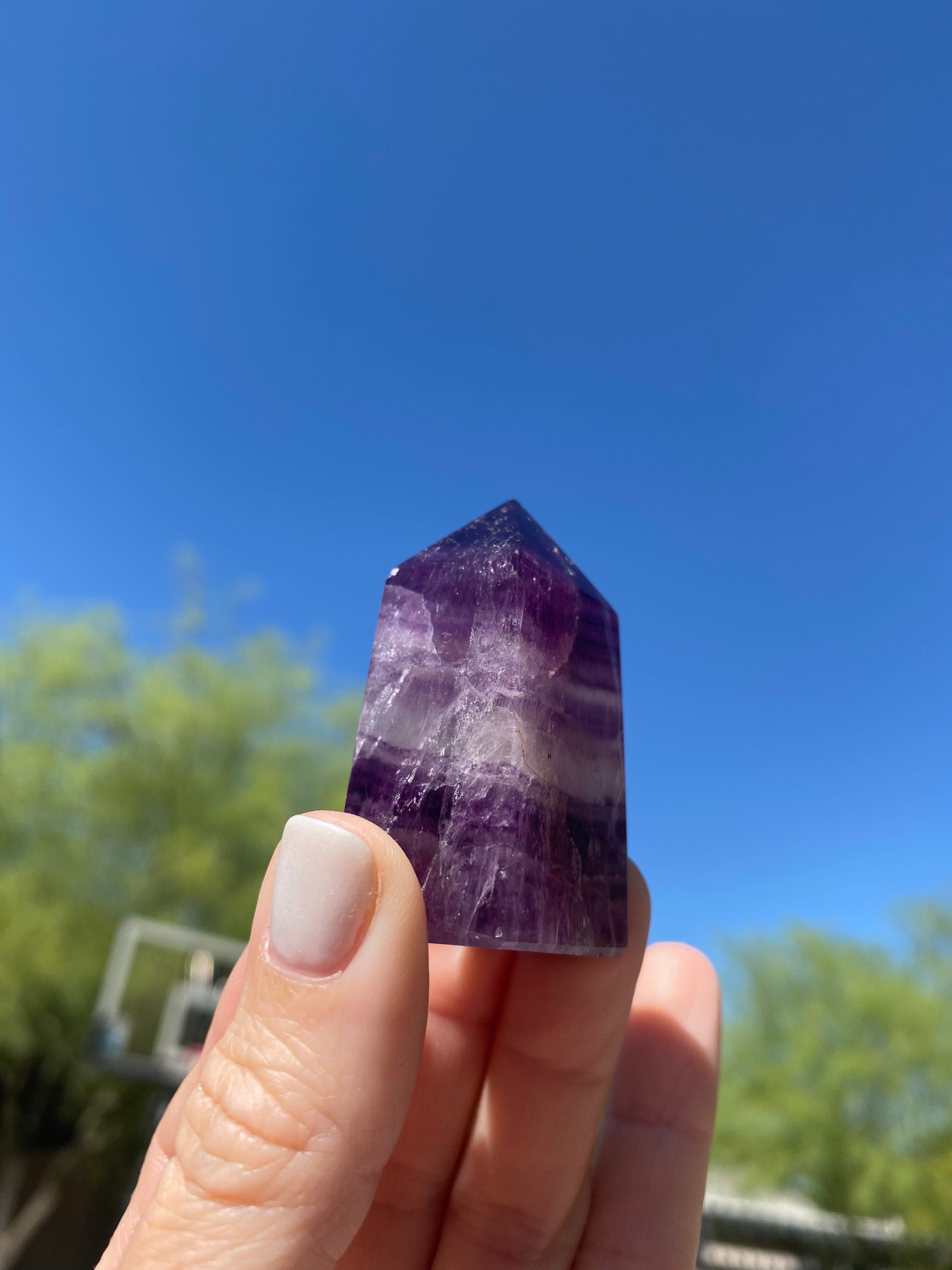 Purple Fluorite Mini Tower shines beautifully under the sun, enhancing its deep violet hues and natural crystal formations