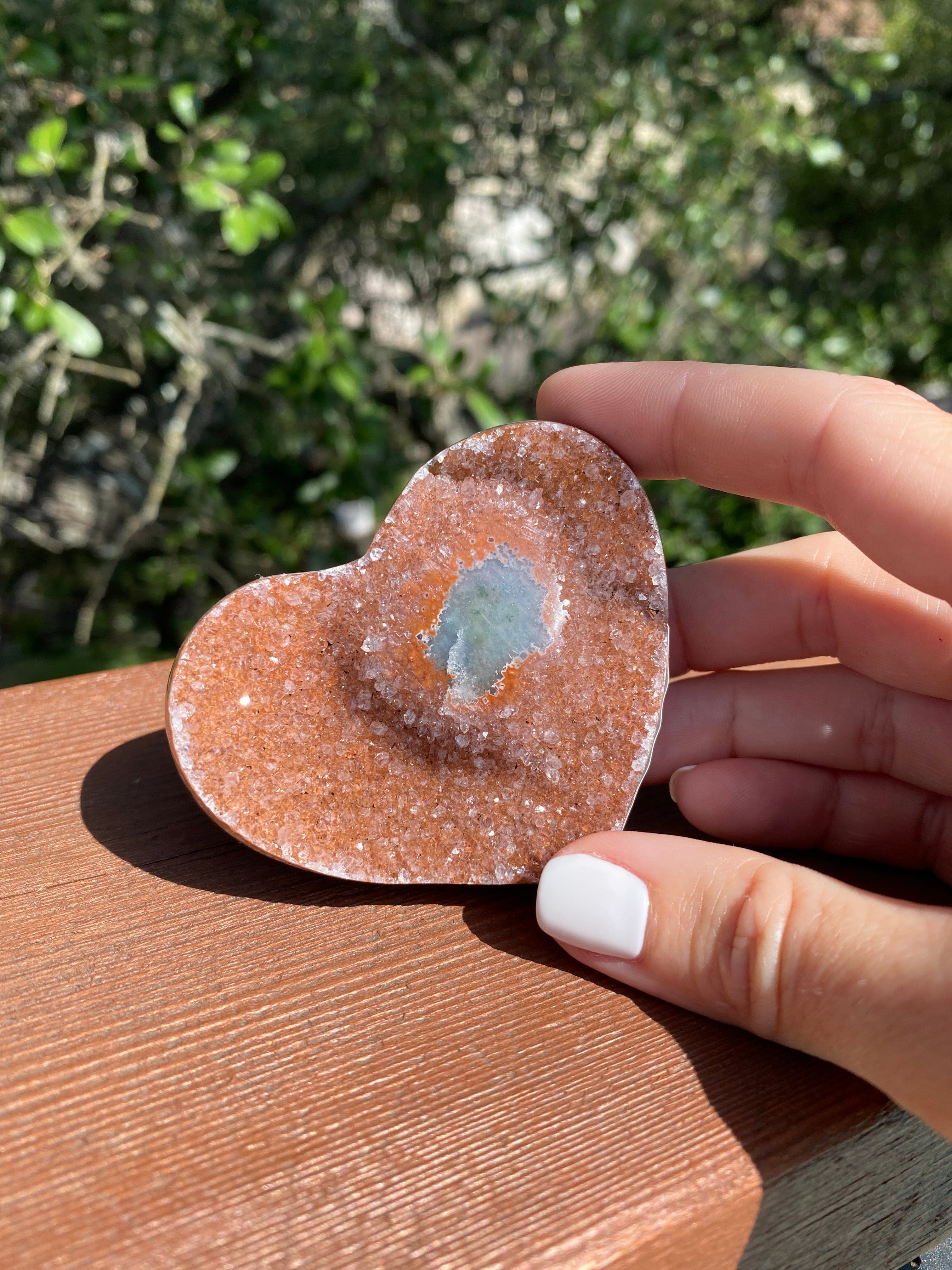 Under the sun, the Lavender and Rose Amethyst Heart glows, revealing its unique Agate core and enhancing its spiritual energy