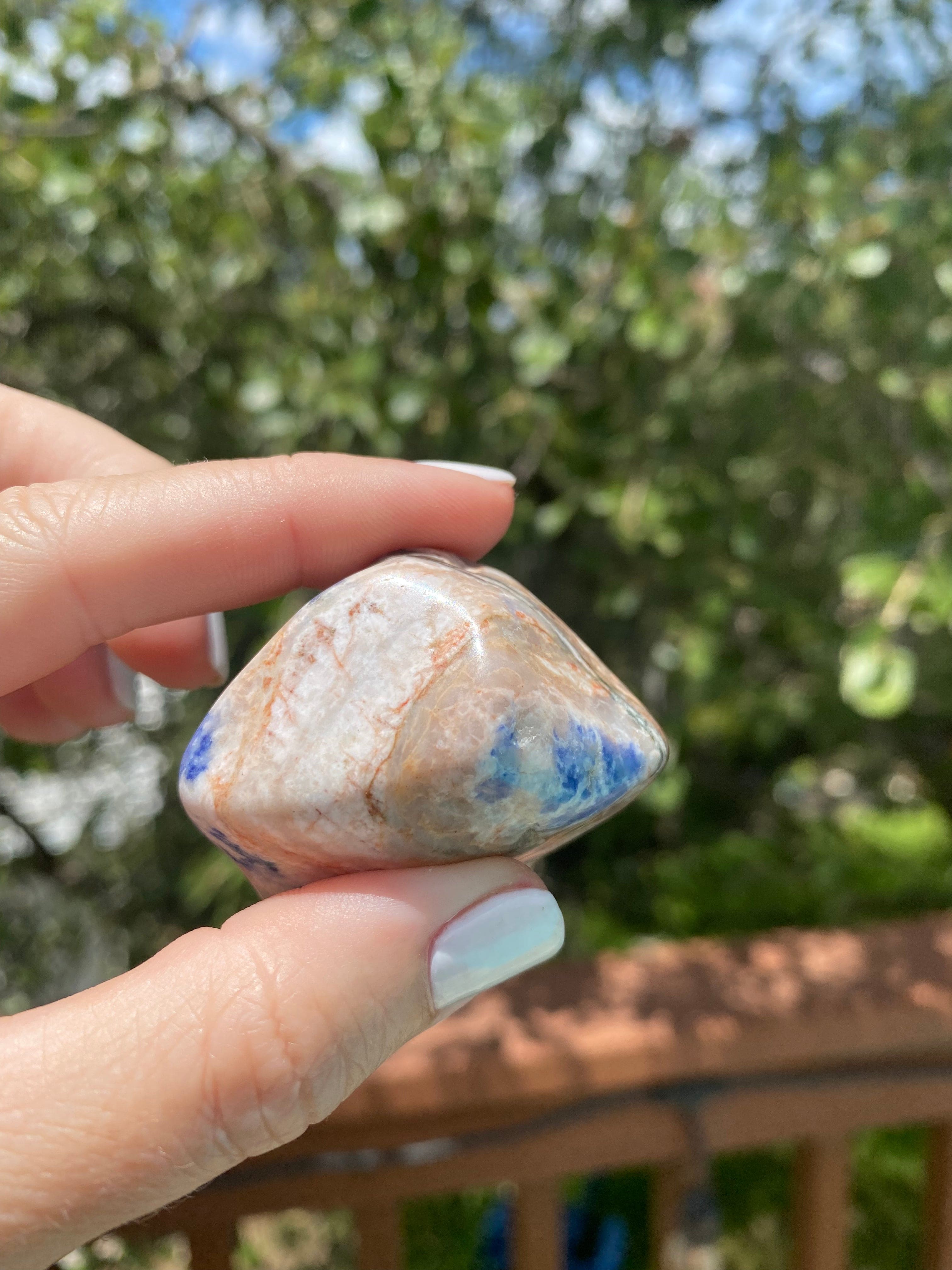 Held up close, the Sodalite Tumble reveals its deep blue hues and white marbling, enhancing calm, emotional balance, and clarity