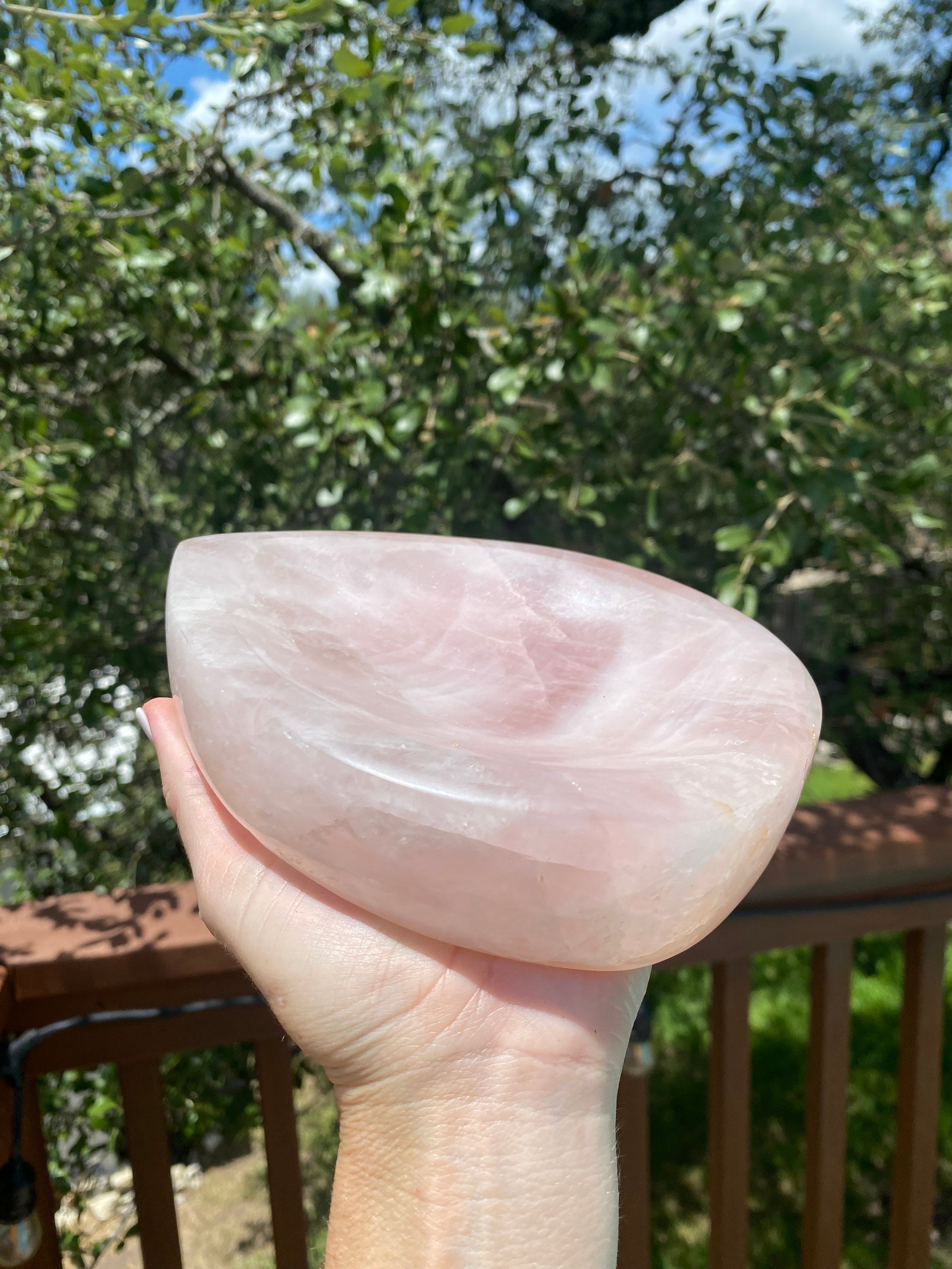 The Rose Quartz Bowl shimmers under sunlight, displaying its tear-drop shape and soft pink glow, perfect for nurturing energy