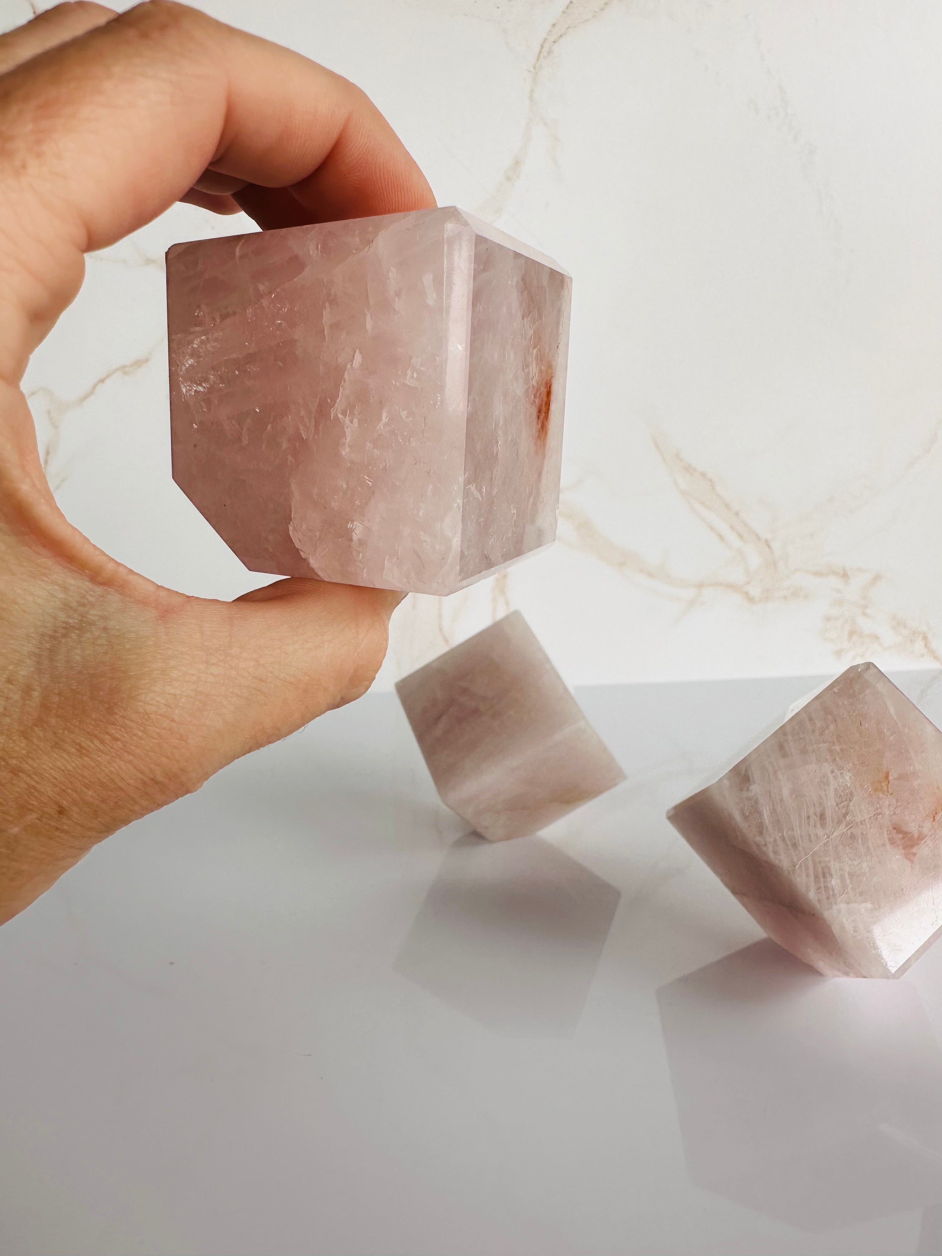 Held close to the camera, the Rose Quartz Cube reveals its smooth, polished surface and intricate details, radiating loving energy